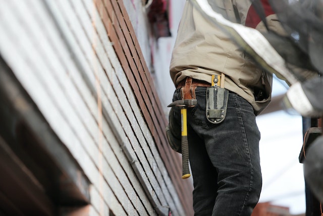 contractor wearing a tool belt standing outside a house